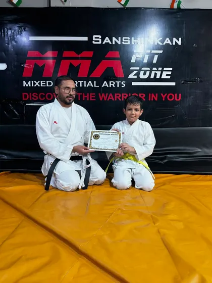 A young boy proudly receives his yellow belt, the first major step in his karate training.