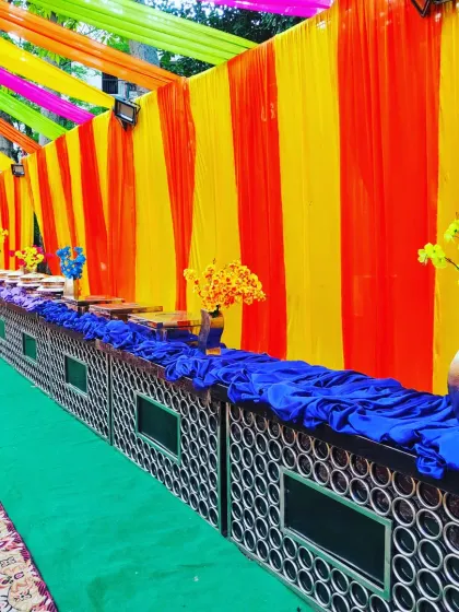 A catering setup for a 'welcome baby' party, showing the colourful tent and the beautifully arranged food counters.