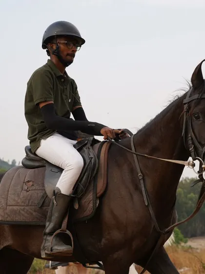 A rider on a dark horse during a trail ride, demonstrating the calm and steady nature of our horses in an outdoor environment.