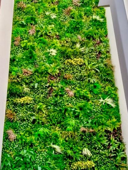 This vertical garden uses a variety of plant types with different shapes and light green tones to create a soft and natural-looking tapestry of foliage.