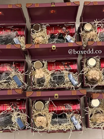 An overhead view of our signature purple trunk hampers being filled with a variety of curated items, showcasing the organized chaos of the festive season.