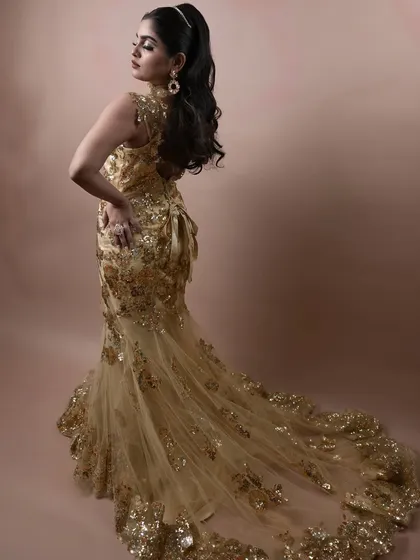 The full view of the golden gown and the elegant, flowing hairstyle. We teach how to style a complete look, not just the makeup.