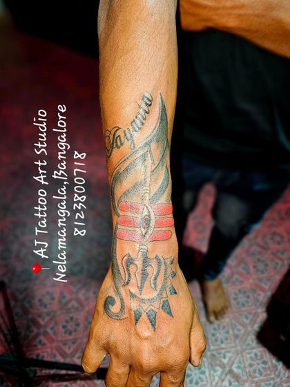 A powerful hand tattoo featuring a Trishul and other spiritual symbols.