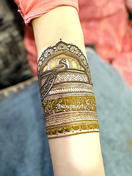 A close-up of an arm band featuring a peacock in a jharokha (window), a classic royal motif.