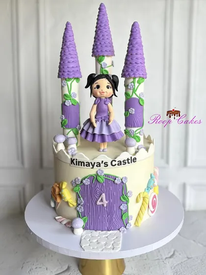 Welcome to Kimaya's Castle, where fairytales come true. This whimsical cake features lavender towers, a princess figurine, and sweet candy details for a magical 4th birthday.