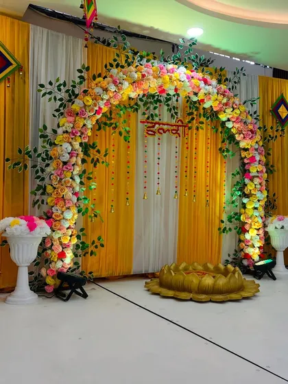 A closer look at the Haldi stage, highlighting the dense floral arch made of marigolds and roses, with hanging floral strings for a traditional touch.