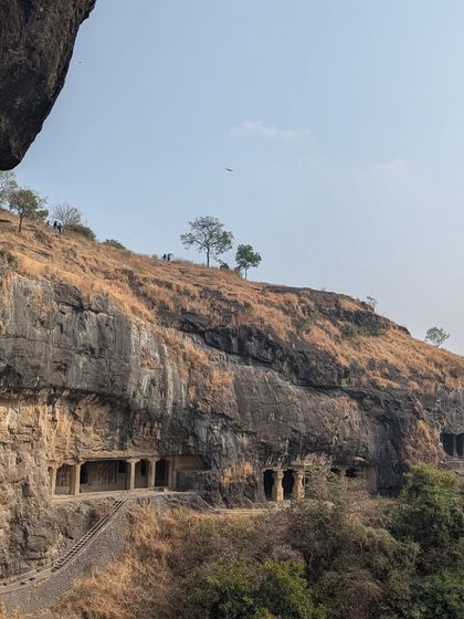 A view of the rock-cut caves from a distance. The way these structures are integrated into the natural cliffside is a lesson in harmony between nature and human creation.