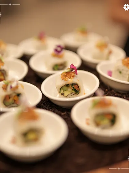 Fresh summer rolls, precisely cut and arranged in small bowls. The colourful vegetables inside are visible through the translucent wrapper, making for a fresh and healthy appetiser.