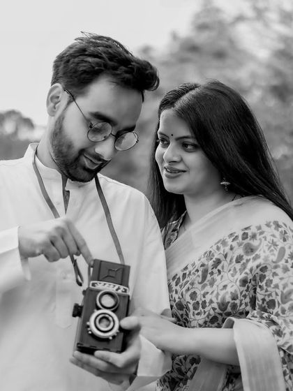 A sweet moment of shared discovery. The groom shows the bride how the vintage twin-lens reflex camera works, creating an engaging and authentic portrait that tells a story.