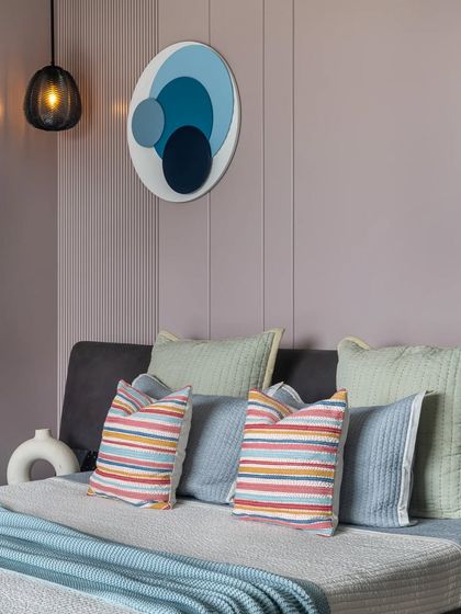 A close-up of the pastel bedroom, showing the custom circular artwork and striped cushions that add a playful yet sophisticated touch of color.
