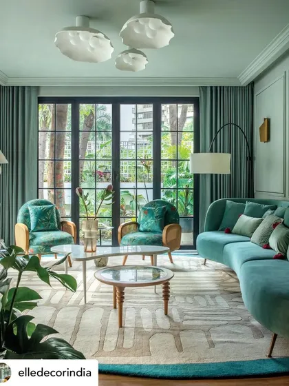 This view of the 'Summer Haus' living room highlights its connection to the outdoors. The lush greenery seen through the French doors complements the interior's color palette, creating a cohesive design that brings the tropical garden inside.