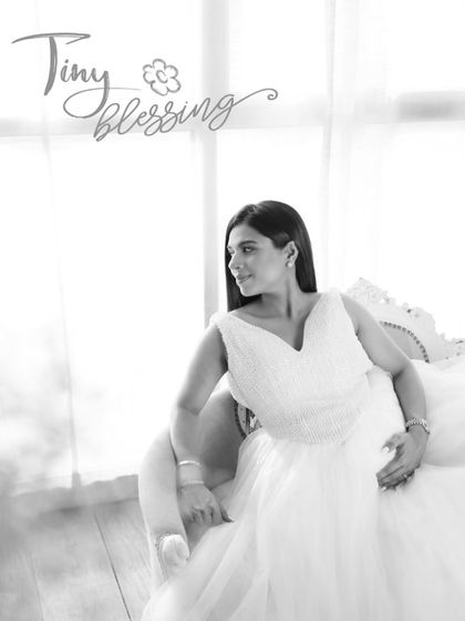A serene and angelic maternity portrait. This black and white image, titled 'Tiny Blessing', captures the peaceful anticipation of motherhood in a fine art style.
