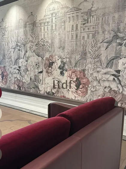 We believe in the power of color psychology. Here, a deep red sofa makes a bold statement against a delicate, large-scale floral and architectural mural. The color choice adds energy and passion to a space grounded in classic elegance.