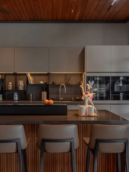 A view of the handleless Porto Matt Lacquer cabinetry and integrated ovens. The open shelving with built-in lighting provides a space for display, adding a personal touch to the minimalist design.