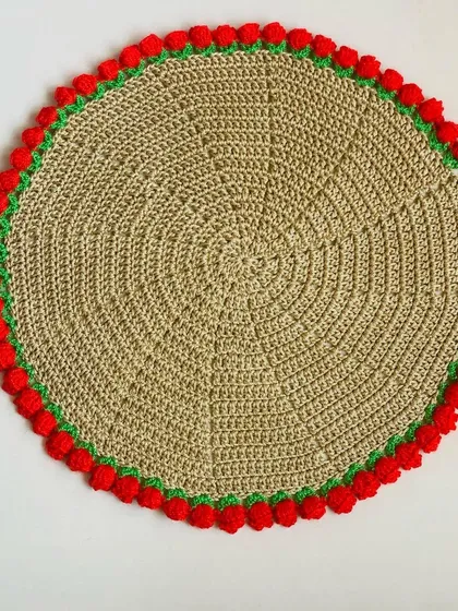 A top-down view of the beige doily with a red tulip border, showing the clean stitch work.