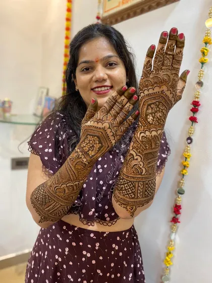 A happy client showing off her full-arm mehendi. The intricate designs are a perfect accessory for her festive attire.