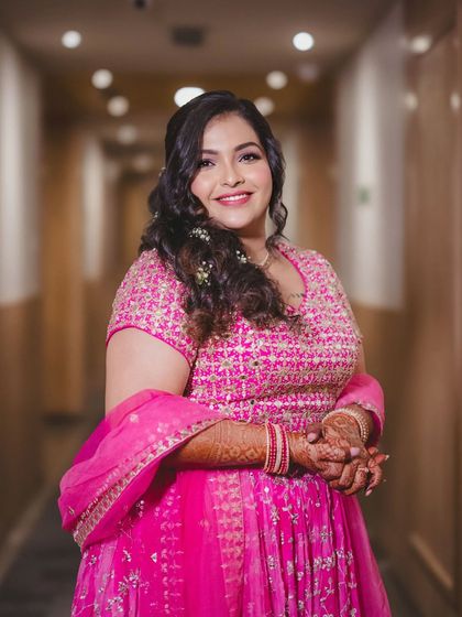 A happy and confident shot in a hotel corridor. The complete look, from hair and makeup to the outfit, is perfect for a Mehendi party.