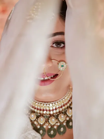 A playful peek from behind the veil. This close-up captures the bride's happy smile and her stunning eye makeup.