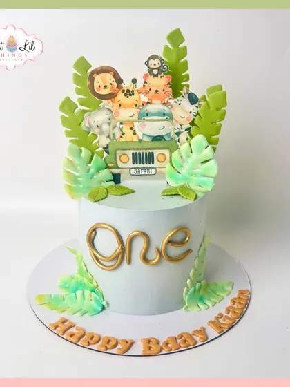 A wild first birthday adventure awaits with this safari-themed cake. Topped with a group of cute, cartoonish jungle animals in a safari jeep, it's a delightful centerpiece for a "Wild One" party.