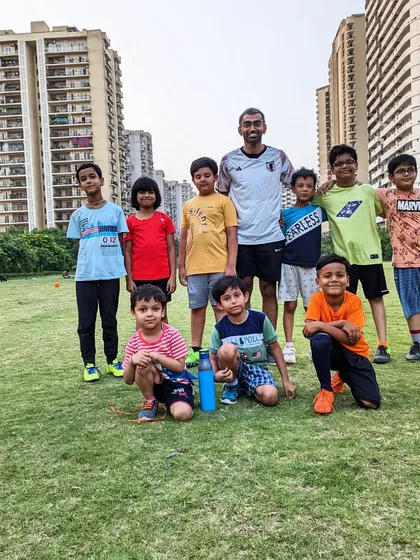 A group of our young players poses with their coach after a rewarding training session on the grass pitch.