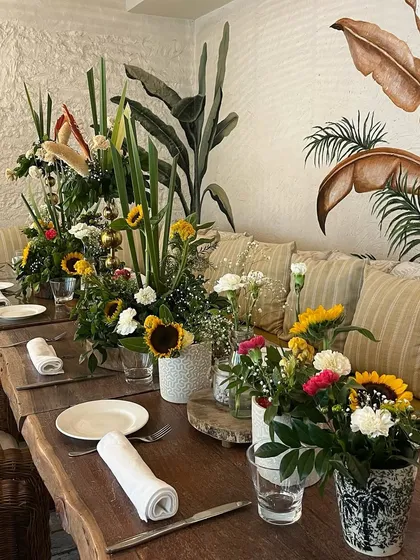 A long shot of the beautiful table setting for the teddy bear themed baby shower. The mix of tall foliage and bright sunflowers creates a stunning, garden like feel indoors.