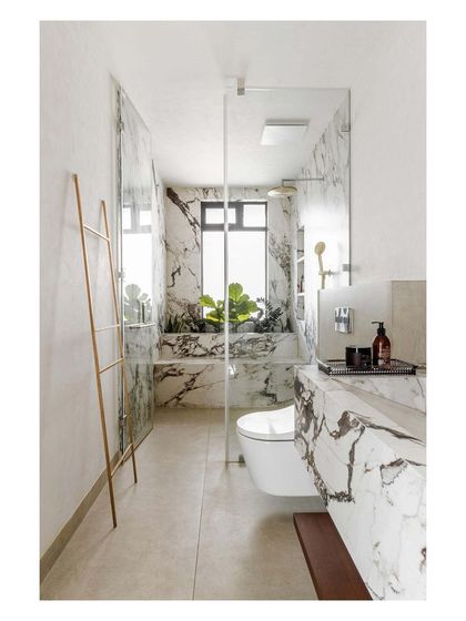 This bathroom uses large-format marble-look tiles to create a seamless and luxurious feel. A glass partition keeps the shower area open and bright.