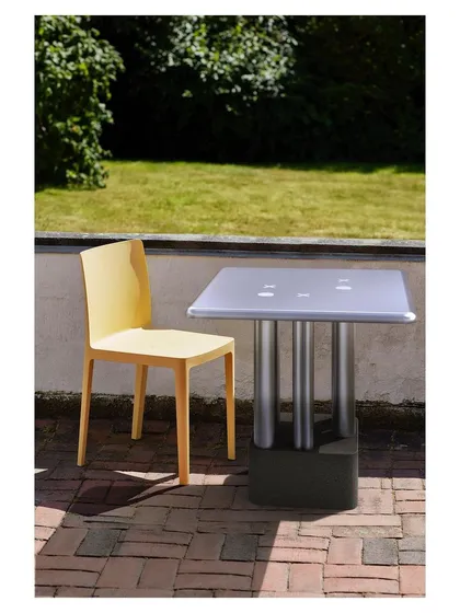 Showcasing its durability, the XOXOX table is placed in an outdoor patio setting. The aluminum construction and concrete block base variant make it perfectly suited for gardens, cafes, and other exterior spaces.