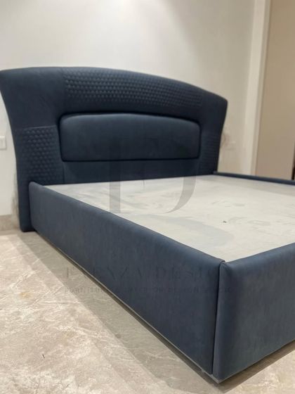 This bed in a deep navy blue features a curved headboard with quilted side panels. It also includes a hydraulic lift mechanism, providing a smart and spacious storage solution.