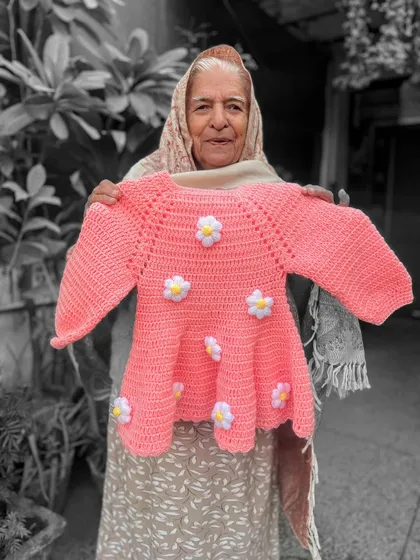 Blooming with cuteness. This pink peplum-style sweater is adorned with little white and yellow daisies, making it a cheerful addition to your child's wardrobe. The selective color effect highlights the warmth of the handmade craft.