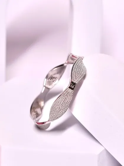 Adorn your wrist with elegance. This timeless silver bangle with a sparkling bow design is a beautiful and sophisticated piece.