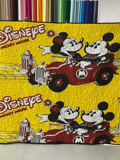 A classic Disney-themed quilt featuring Mickey and Minnie Mouse on a bright yellow background.