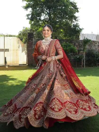 A happy bride twirling in her magnificent lehenga. This shot captures the joy and the grandeur of the outfit in a beautiful outdoor setting.