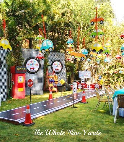 An outdoor "Cars" party setup with a mini road for kids to play on and hanging car decorations. The entire space was transformed into a fun traffic jam.