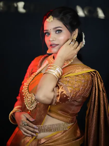 A confident portrait of a model in a South Indian bridal look. The makeup is bold and beautiful, designed to stand out against the heavy gold jewelry.