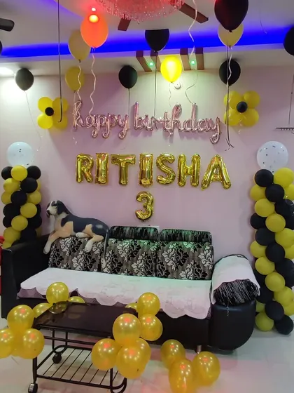 A simple yet fun birthday setup in yellow and black. This decoration uses balloon pillars and scattered balloon clusters, along with foil letters for the name and age, to fill the space with color.