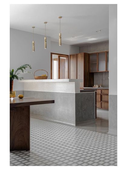 The transition from a patterned tile floor in the dining area to a smooth polished concrete floor in the kitchen. This careful detailing at the threshold defines the two spaces while maintaining a cohesive flow.