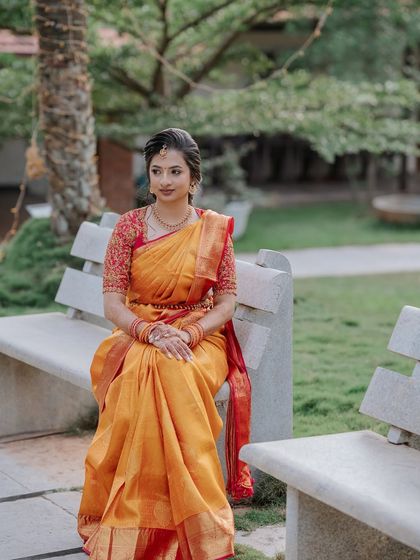A full portrait of the bride seated, her elegant posture and the beautiful fall of the saree on display.