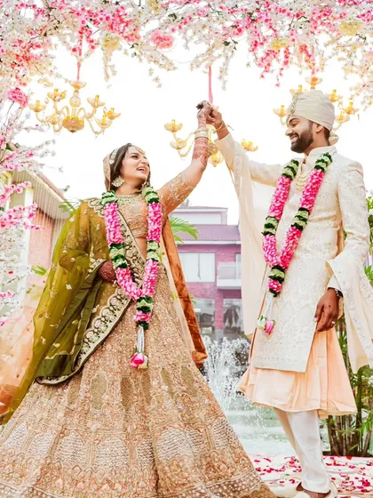 A joyful moment right after the Varmala ceremony. The couple dances under a canopy of cherry blossoms, their smiles reflecting the happiness of being officially united.