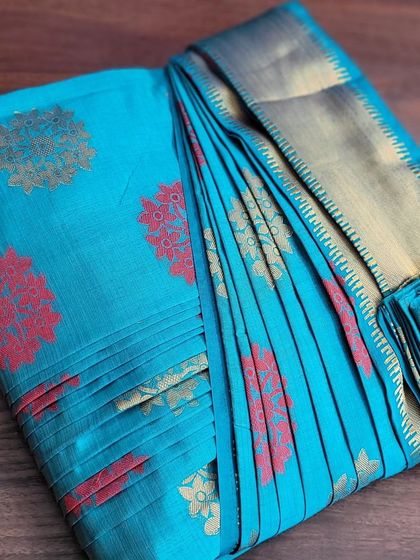 A close-up of a student's work on a bright turquoise saree.