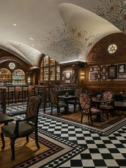 The pub's interior is a journey through different textures and patterns, from the checkerboard floor to the carved wood and floral wallpaper.