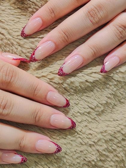 A chic and modern French manicure. The tips are filled with a sparkling red glitter, offering a festive and glamorous twist on the timeless style.