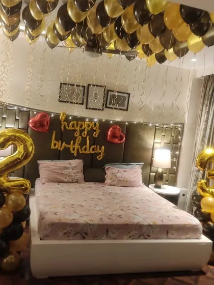 I also offer surprise room decorations to make your loved one's day special. This bedroom setup includes black and gold balloons on the ceiling, large "28" foil number balloons, and a "Happy Birthday" sign over the bed.