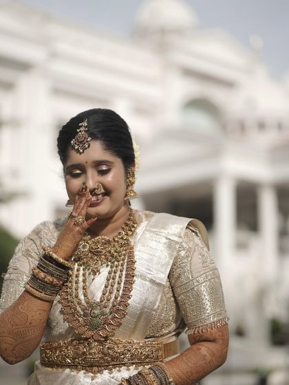A candid moment of the bride, looking absolutely radiant in her off-white silk saree and antique temple jewellery.