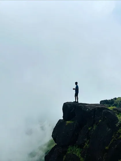 A lone trekker on a cliff edge at Kumara Parvatha, a classic "on top of the world" shot.