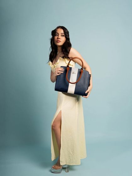 A full-length shot that showcases how the Lavie handbag complements a complete outfit. The simple background keeps the focus on the fashion.