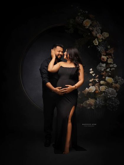 A romantic couple's portrait with a beautiful floral hoop. The dark, moody lighting creates an intimate and sophisticated atmosphere.