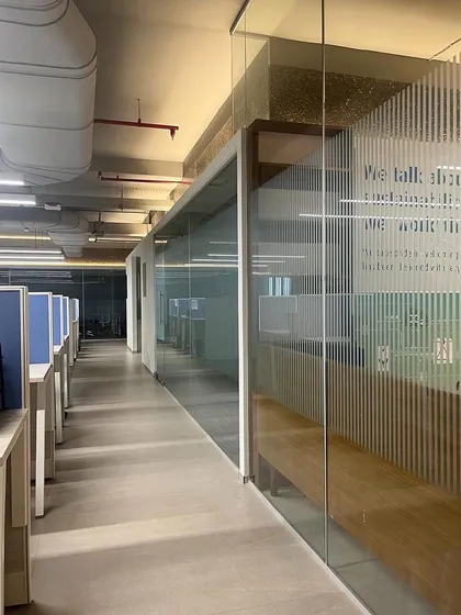 This corridor in the Umicore office showcases the open and transparent design. The exposed ceiling and ductwork add an industrial touch, while the glass walls maintain a sense of connection across the workspace.