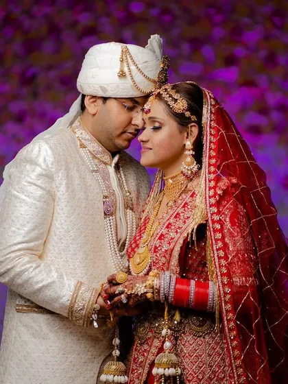 An intimate and romantic portrait against a vibrant purple floral background. The couple's close embrace creates a beautiful, emotional shot.
