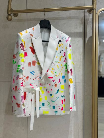 The abstract neon blazer hanging in the studio. The bright colors and splatter effect give it a fun, 80s-inspired vibe.