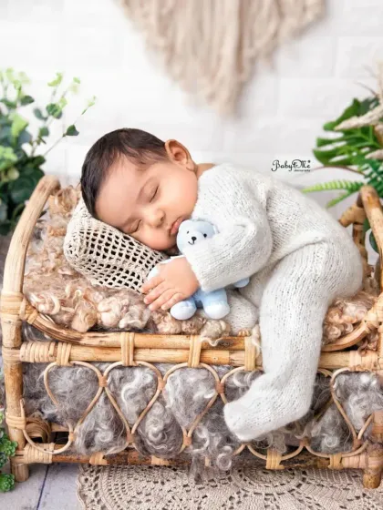 Another peaceful moment from a newborn session, with the baby sleeping on a miniature bed holding a tiny blue bear. These detailed setups create such magical portraits.